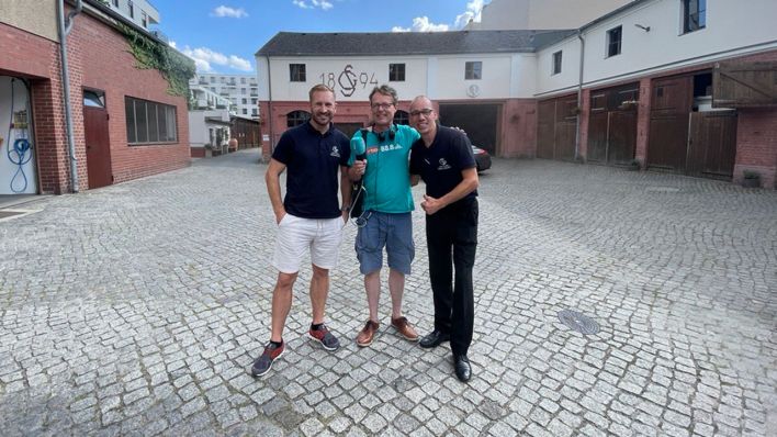 Letzte Station: der Bestatter am Richardplatz. Alex mit Benjamin und Andi von der Firma Gustav Schöne Braut-, Automobil-, Beerdigungs- und Arbeitsfuhrwesen gegründet 1894. Sie haben die Kieztour im Radio verfolgt und sich sehr gefreut, als Alex auf dem Hof stand. (Foto: rbb 88.8)